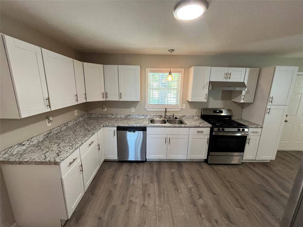 1843 Greendale Drive, Dallas, TX 75217 White shaker-style cabinetry with matte hardware, stone-look countertops, stainless steel appliances, and wood-finish flooring