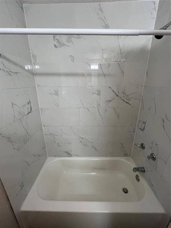 1843 Greendale Drive, Dallas, TX 75217 Bathtub with a white finish, white and gray patterned wall tile, and chrome fixtures