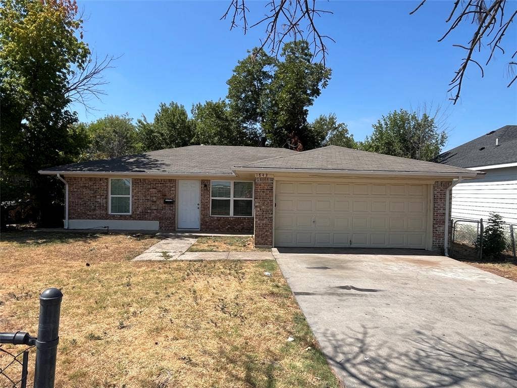 1843 Greendale Drive, Dallas, TX 75217 Brick exterior with a light-colored garage door, concrete driveway, and a white entry door