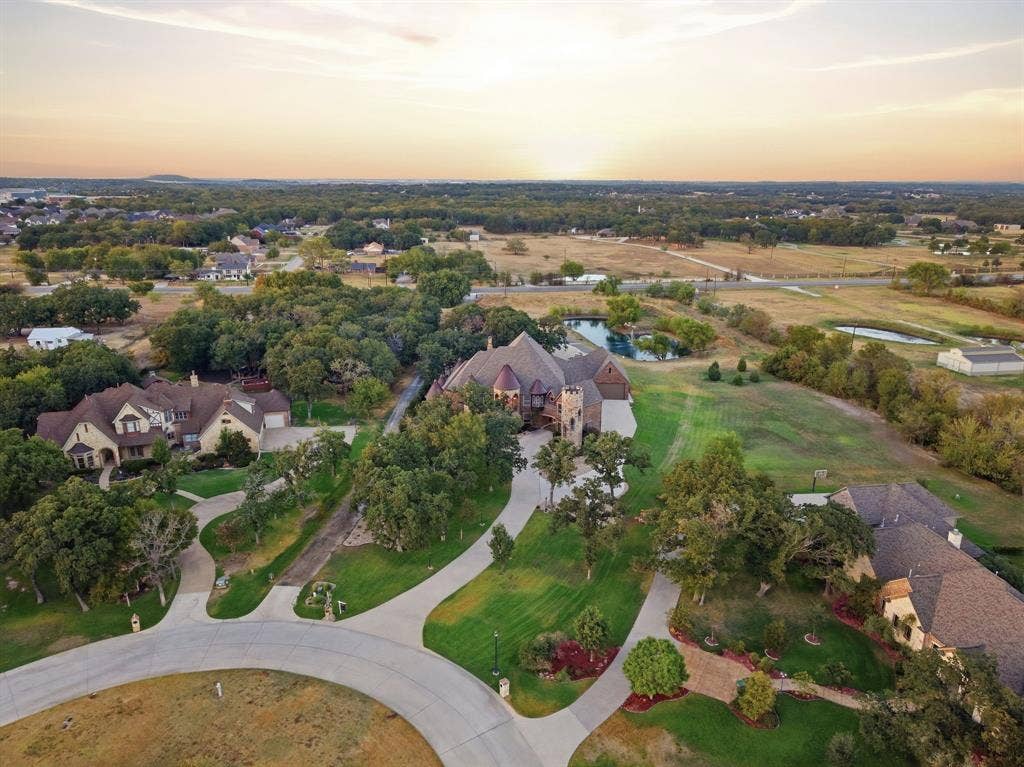Expansive property featuring a private pond, mature trees, manicured lawns, and concrete driveways