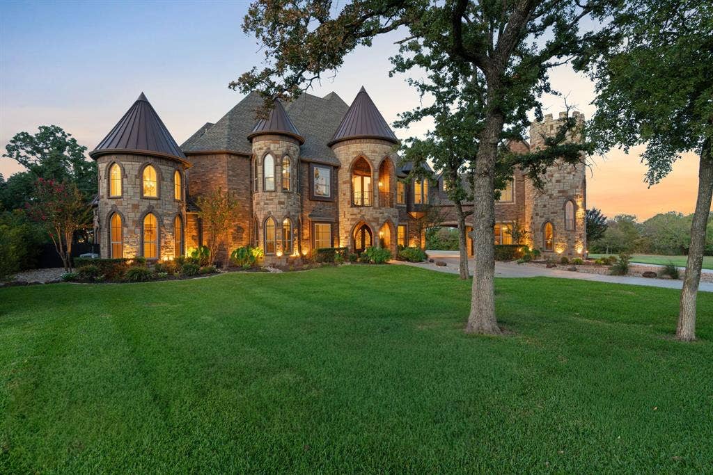 Stone exterior residence featuring multiple turrets with conical roofs, arched windows, and a paved drive