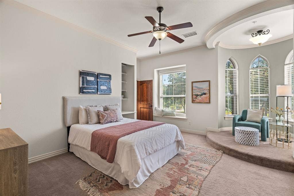 2nd floor bedroom with recessed ceiling feature, arched windows, built-in shelving, ceiling fan light fixture, and window seat. This room has a closet in the bedroom and another closet in the en-suite bathroom