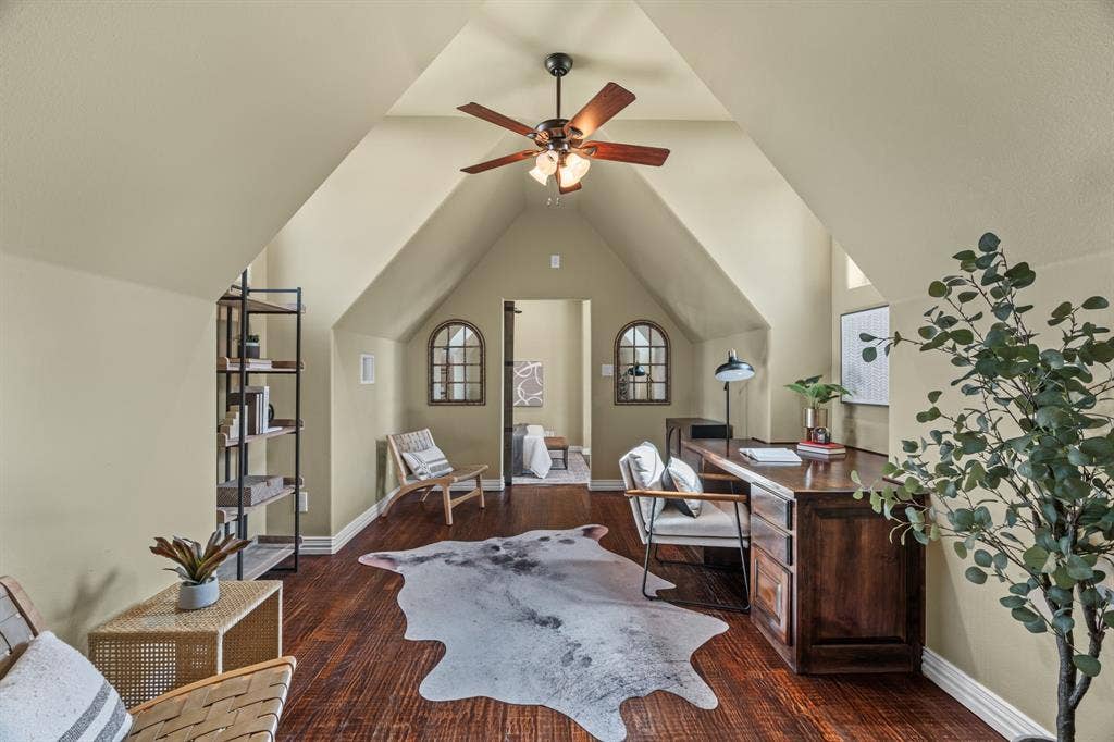 Secondary living space accessible from upstairs with  vaulted ceilings, wood-finish flooring, ceiling fan with light fixture, and arched windows