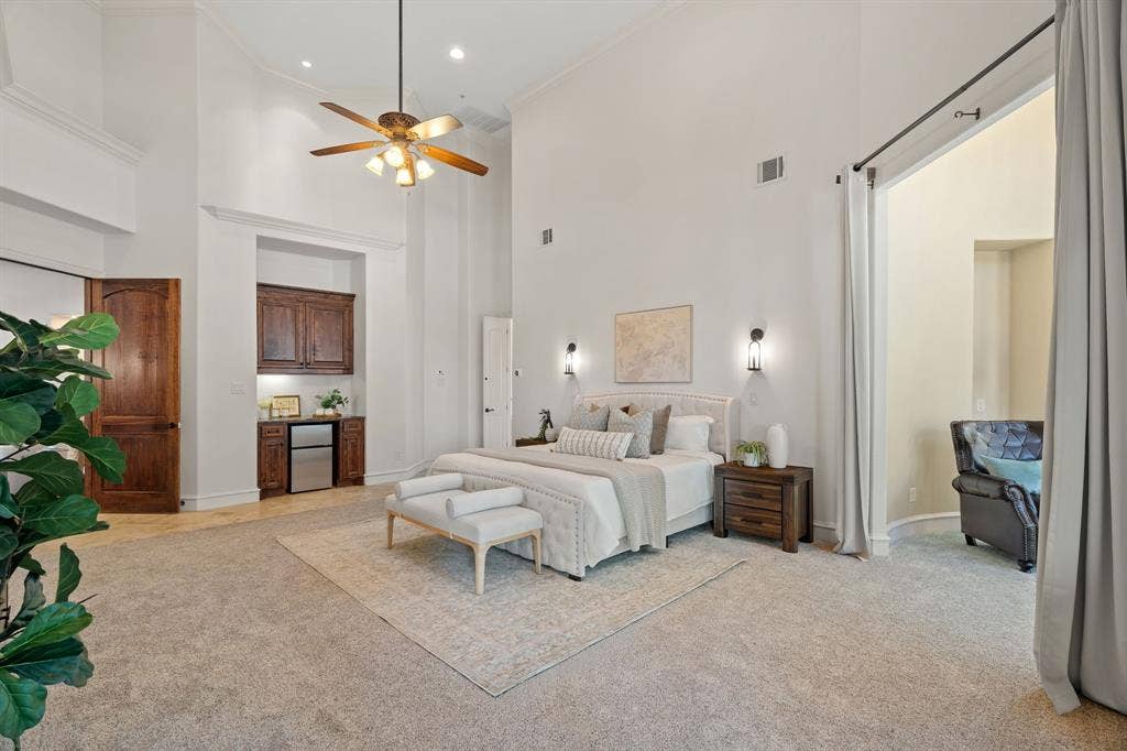 Vaulted ceilings with recessed lighting, ceiling fan, and wall sconces, sitting area, wet bar and exterior access to patio