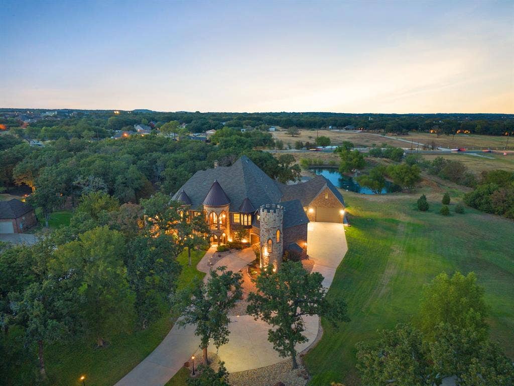 Custom stone-clad residence featuring a turret and multiple gables, circular driveway and porte-cochere