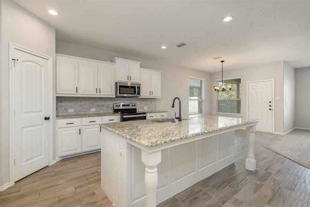 928 Dove Cove, Argyle, TX 76226 View of kitchen and dining area. Large kitchen island with designated sitting area, sink, granite countertops.