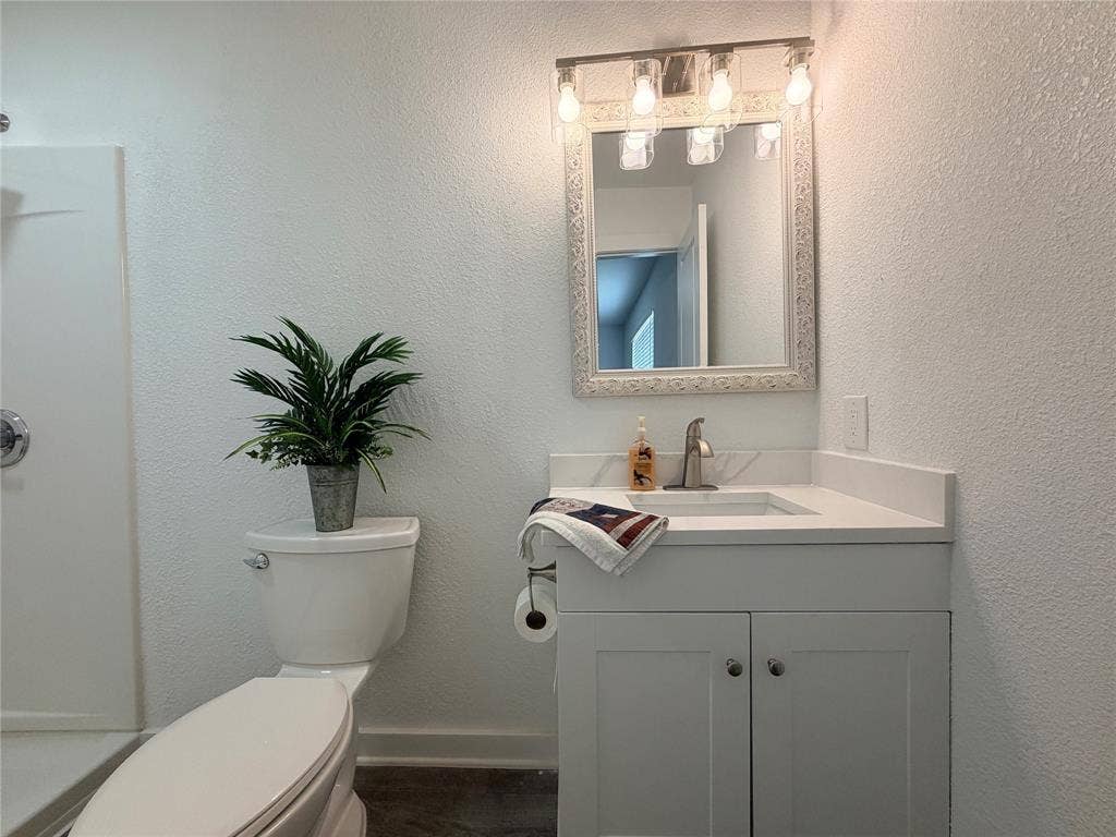 White vanity with a quartz countertop and integrated sink, framed mirror, and brushed nickel hardware