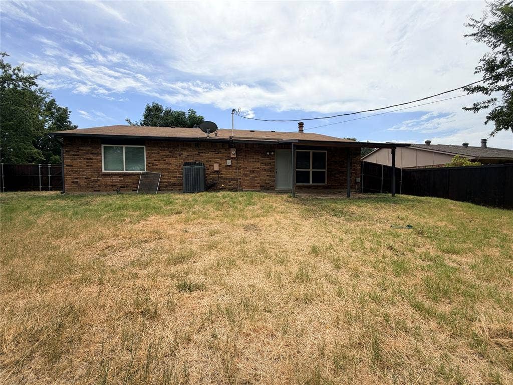 Brick exterior with a covered patio and a partially fenced yard