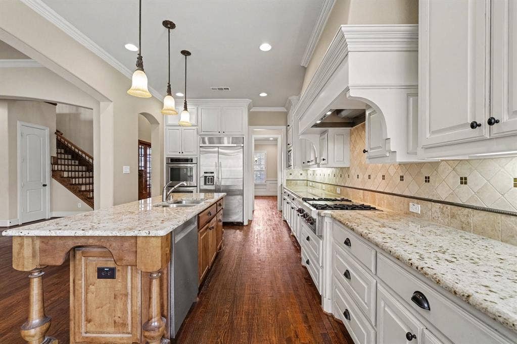 408 Blue Ridge Court, Allen, TX 75013 Hardwood flooring, light-toned countertops, white cabinetry, stainless steel appliances, and a tiled backsplash