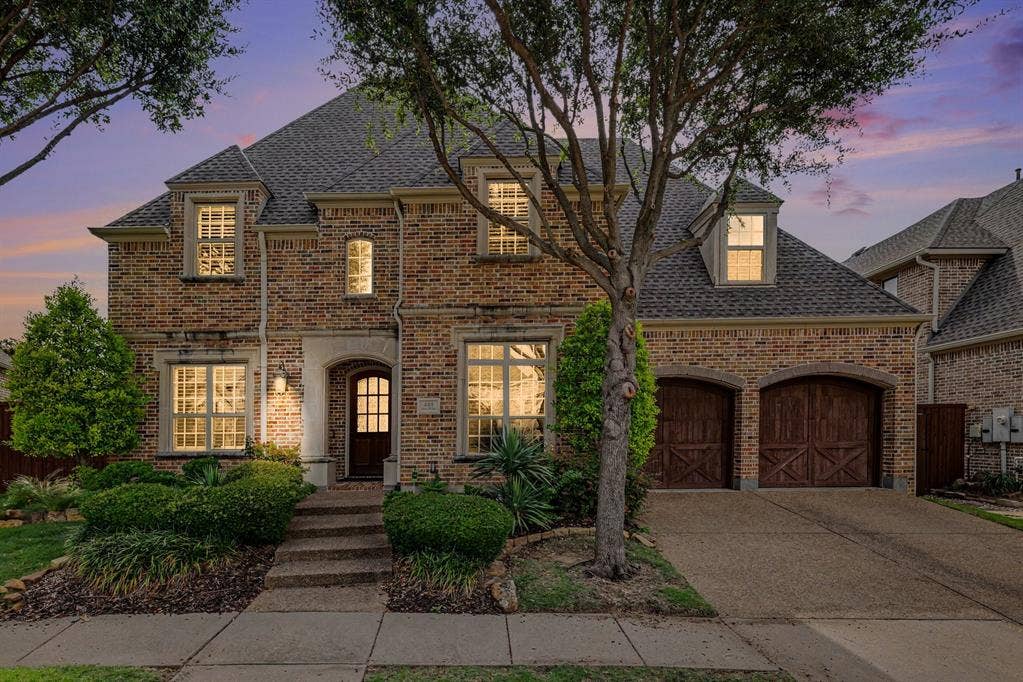 408 Blue Ridge Court, Allen, TX 75013 Brick exterior with stone accents, arched entry, dark wood front door, and two-car garage with arched wood doors