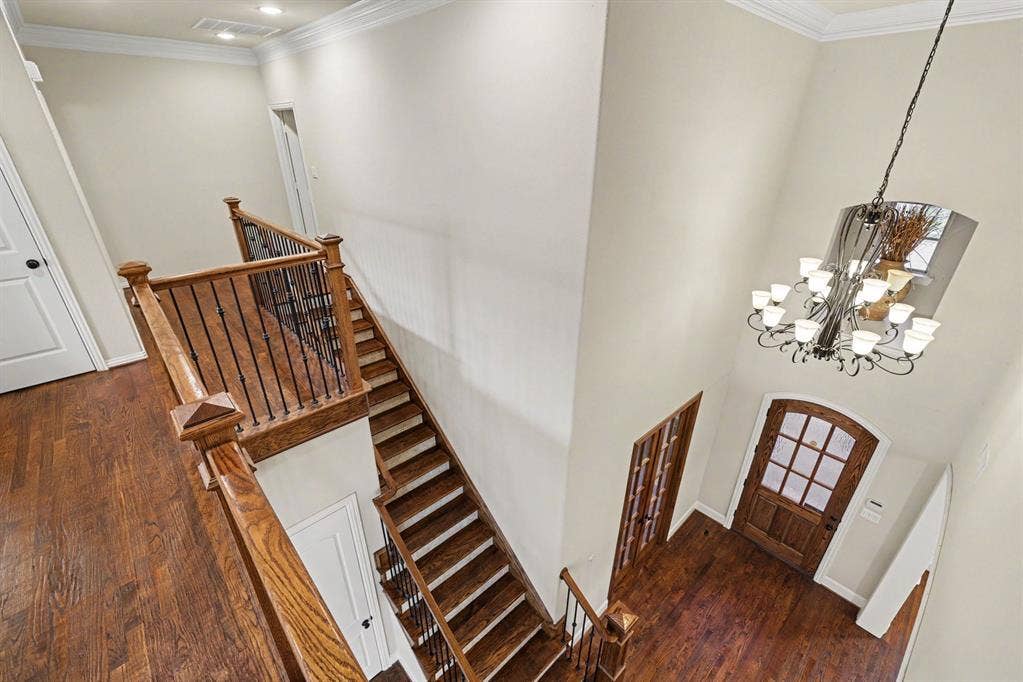 408 Blue Ridge Court, Allen, TX 75013 Two-story entryway with a wood-finish staircase featuring wrought iron balusters, a wood-finish front door with glass panels, and a multi-arm chandelier