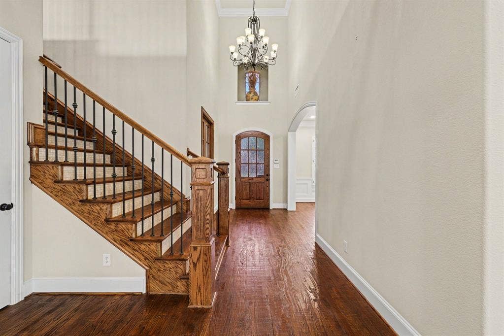 408 Blue Ridge Court, Allen, TX 75013 Hardwood flooring, wood staircase with iron balusters, arched doorway, wood entry door with glass panels, and a high ceiling