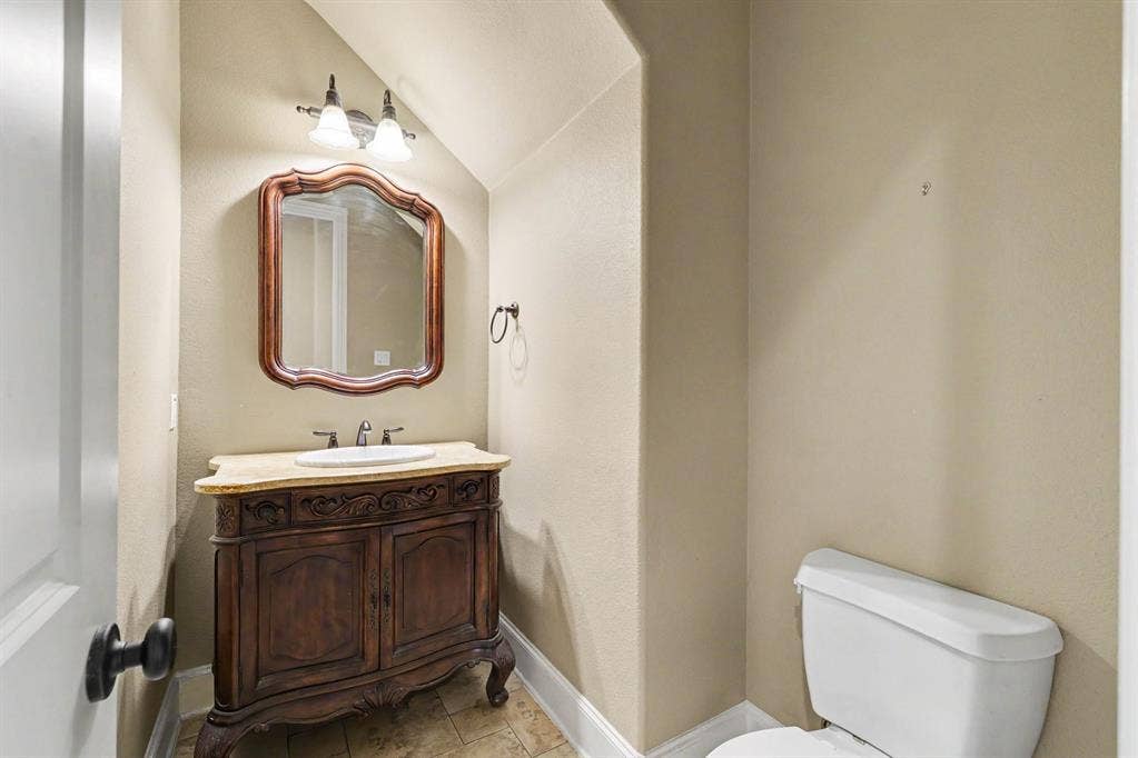 408 Blue Ridge Court, Allen, TX 75013 Ornate vanity with integrated sink, framed mirror, wall-mounted light fixture, and tiled flooring