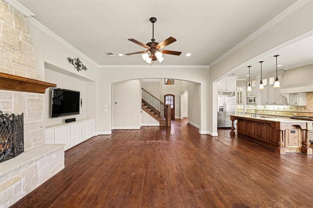 408 Blue Ridge Court, Allen, TX 75013 Hardwood flooring throughout, stone fireplace with custom mantel, built-in media cabinetry, open archway to kitchen, and a wooden staircase with iron balusters