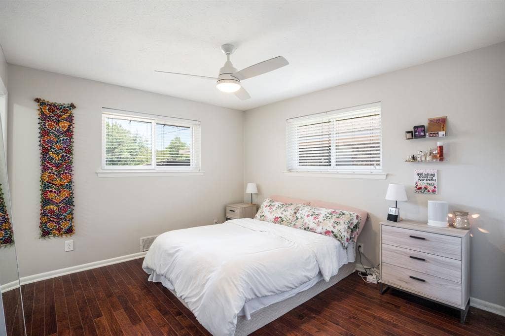 2711 Alco Avenue, Dallas, TX 75211 Bright secondary bedroom featuring hardwood flooring, ceiling fan with integrated lighting, dual windows with plantation shutters, and coordinating built-in dresser with three drawers