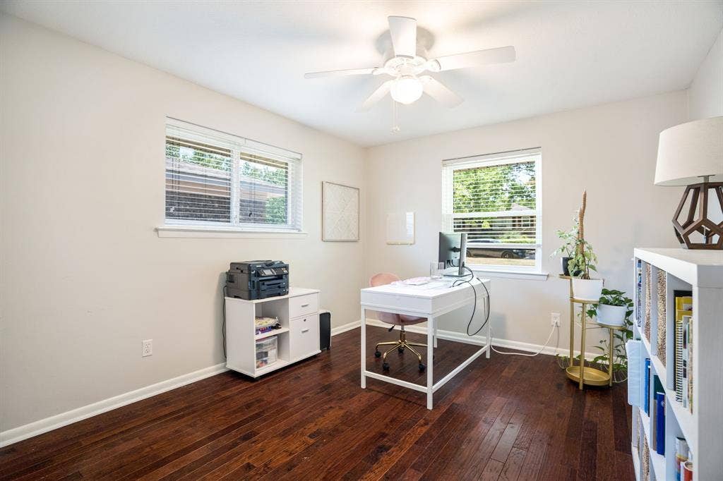 2711 Alco Avenue, Dallas, TX 75211 Dark wood-finish flooring, white walls, two windows with blinds, and a ceiling fan with light fixture