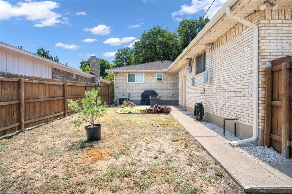 2711 Alco Avenue, Dallas, TX 75211 Backyard featuring a privacy fence, concrete walkway, and a brick exterior