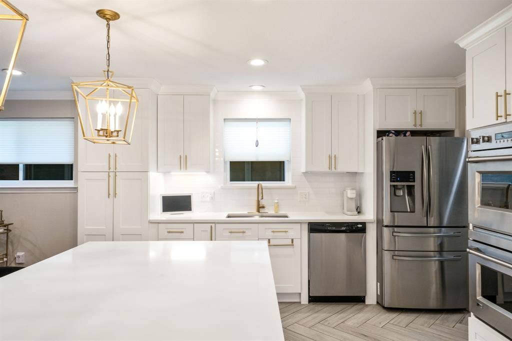2711 Alco Avenue, Dallas, TX 75211 Kitchen featuring white cabinetry, stainless steel appliances, a white tile backsplash, a large kitchen island, and wood-finish flooring