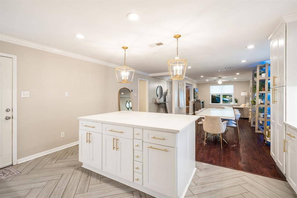 2711 Alco Avenue, Dallas, TX 75211 Kitchen island with white cabinetry, gold-tone hardware, and a solid surface countertop