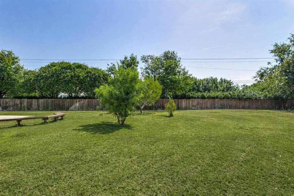 9604 Bull Creek Drive, Plano, TX 75025 Expansive green lawn with a privacy fence and mature trees