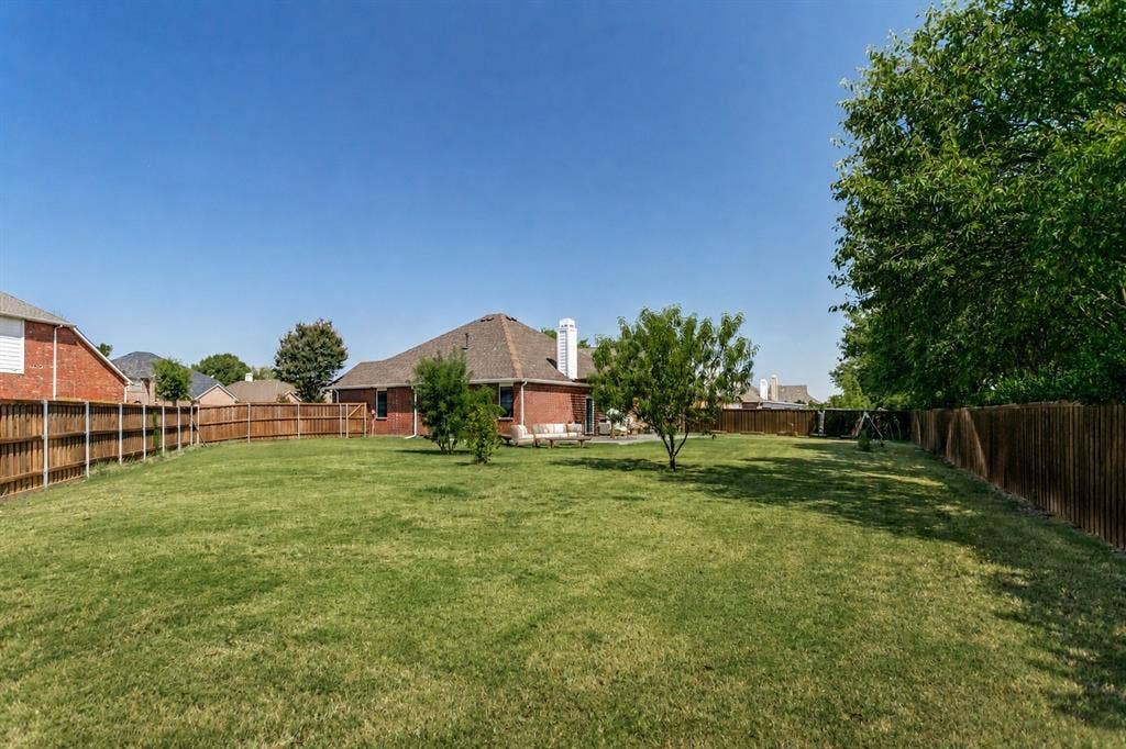 9604 Bull Creek Drive, Plano, TX 75025 Expansive backyard with a manicured lawn, full wood fencing, and mature trees
