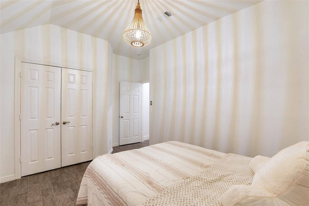 Wood-finish flooring, white paneled bifold closet doors, and a decorative pendant light fixture