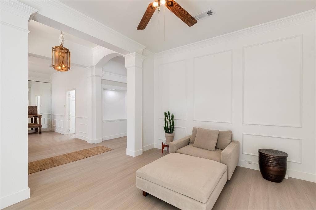 Recessed archway, wood-finish flooring, decorative wall paneling, ceiling fan with wood-finish blades, and a built-in light fixture