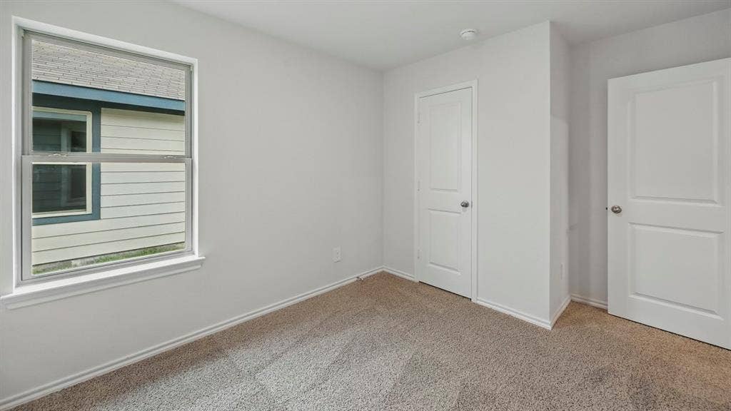 1912 Freeman Street, Tyler, TX 75702 Neutral-toned carpeting, white interior doors, and a window with white trim