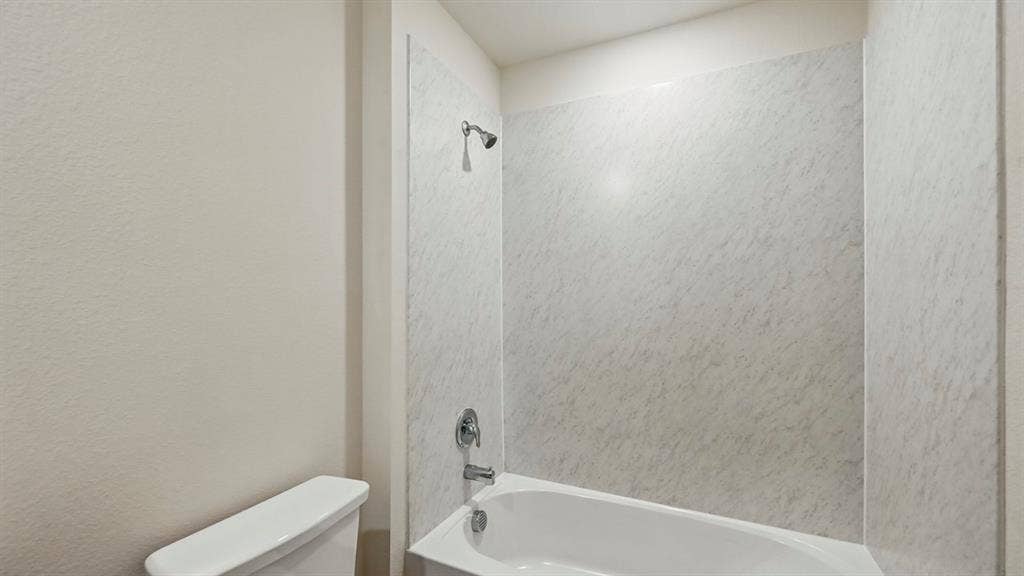 1912 Freeman Street, Tyler, TX 75702 White ceramic toilet with a matching bathtub and shower surround, featuring chrome fixtures