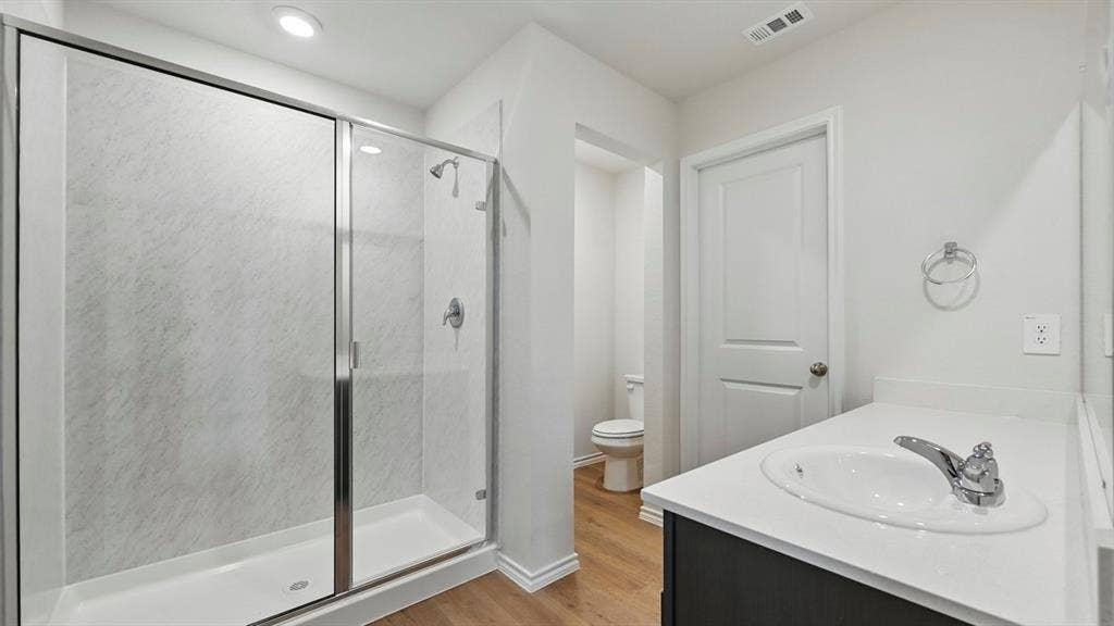 1912 Freeman Street, Tyler, TX 75702 Shower with glass enclosure, single vanity with white countertop, and wood-finish flooring