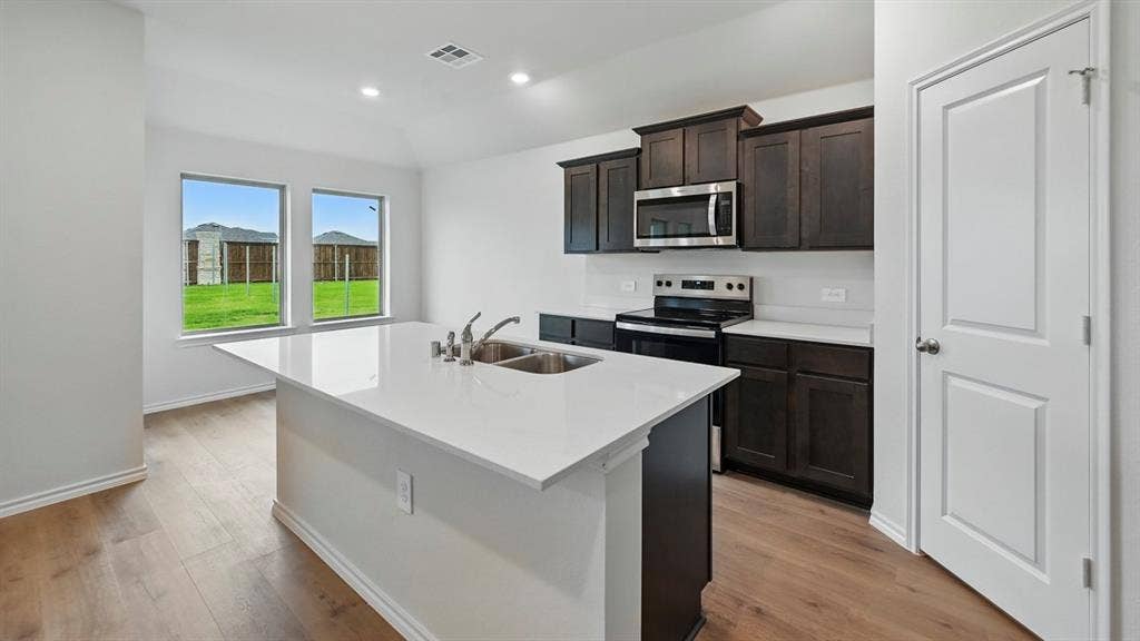 1912 Freeman Street, Tyler, TX 75702 Kitchen featuring a center island with sink, dark wood-finish cabinetry, stainless steel appliances, wood-finish flooring, and recessed lighting