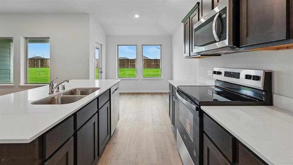 1912 Freeman Street, Tyler, TX 75702 Kitchen featuring white countertops, stainless steel appliances, dark wood-finish cabinetry, a double basin sink, and wood-finish flooring