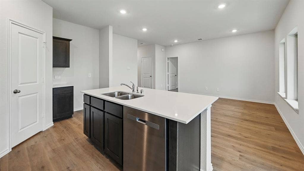 1912 Freeman Street, Tyler, TX 75702 Kitchen island with a double basin sink, stainless steel dishwasher, and dark wood-finish cabinetry
