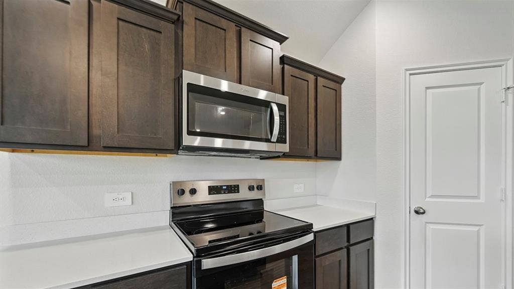 1912 Freeman Street, Tyler, TX 75702 Stainless steel microwave, stainless steel electric range, dark wood-finish cabinetry, white countertops, and white door