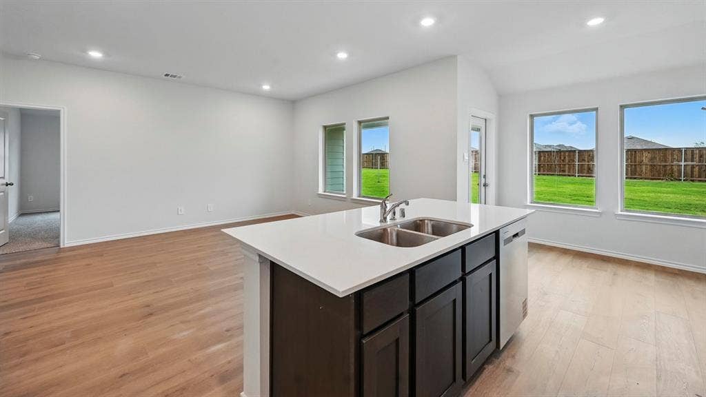 1912 Freeman Street, Tyler, TX 75702 Open-concept living space featuring wood-finish flooring, recessed lighting, a kitchen island with a double basin sink, and large windows with backyard views
