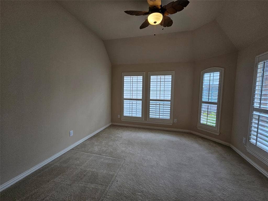 1009 Ricci Court, Irving, TX 75062 Carpeted room featuring multiple windows with plantation shutters, a ceiling fan, and sloped ceiling details