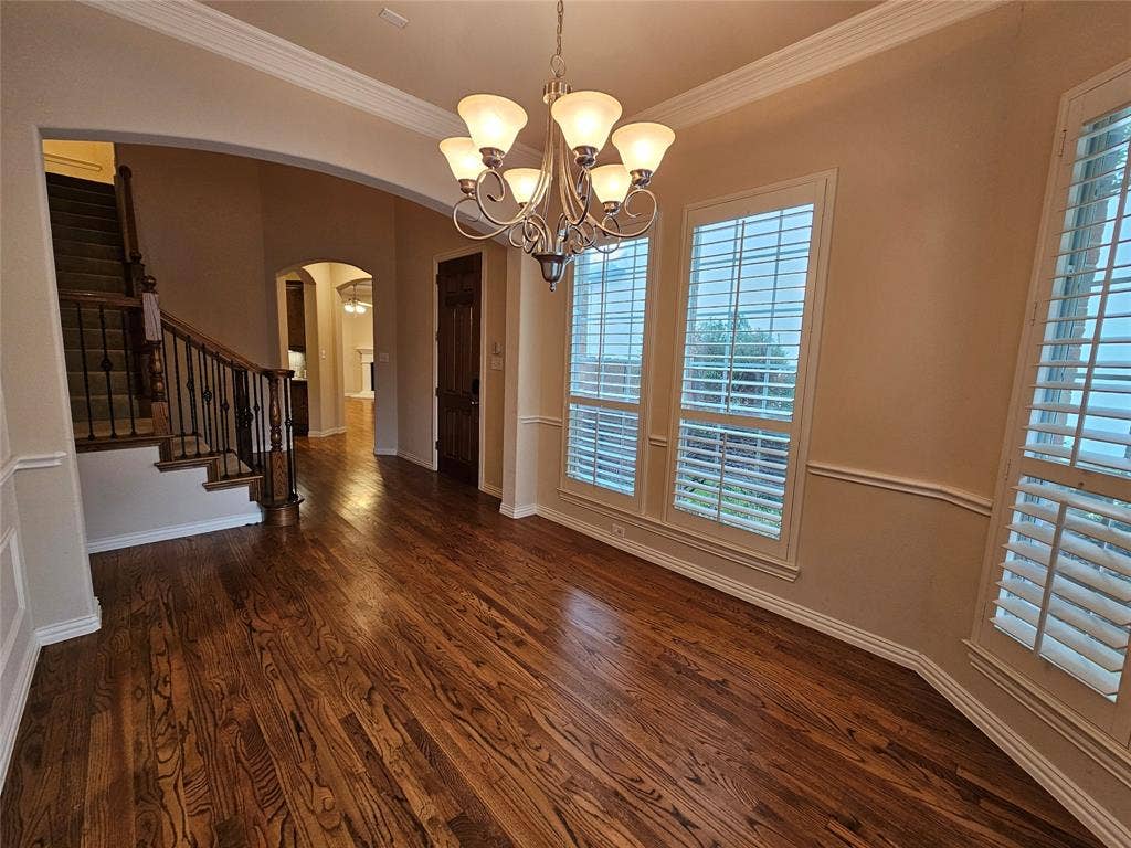 1009 Ricci Court, Irving, TX 75062 Hardwood flooring, decorative chandelier, bay windows with plantation shutters, crown molding, and wainscoting