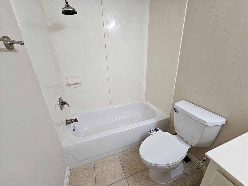 1009 Ricci Court, Irving, TX 75062 White bathtub with a shower fixture, tile flooring, and a toilet