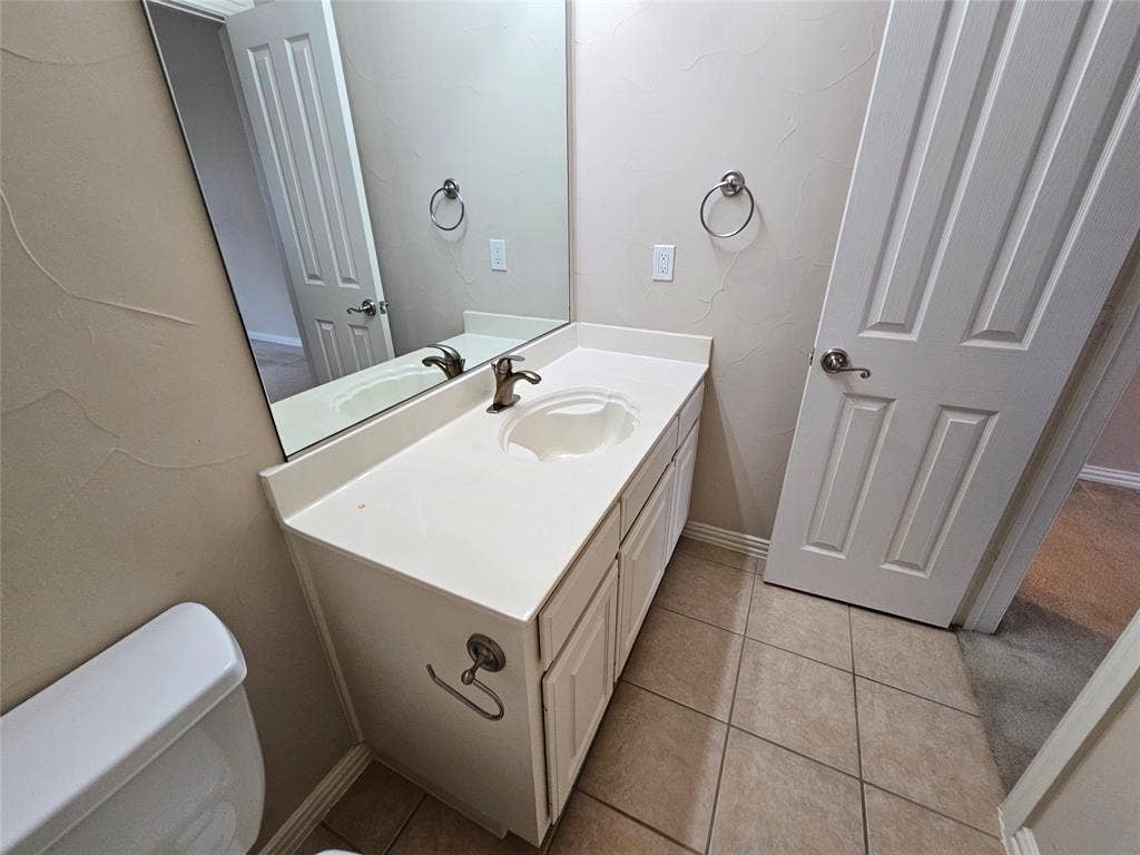 1009 Ricci Court, Irving, TX 75062 Vanity with an integrated sink, brushed nickel faucet, and a large wall-mounted mirror