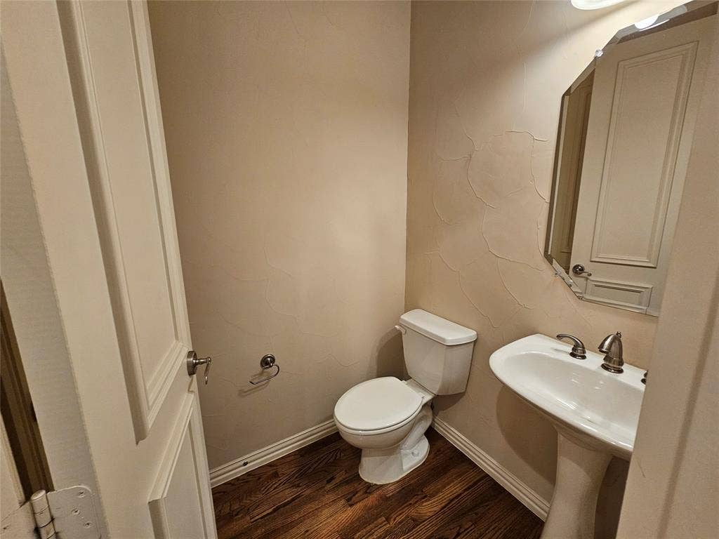1009 Ricci Court, Irving, TX 75062 Wood-finish flooring with white trim, pedestal sink, and decorative wall texture