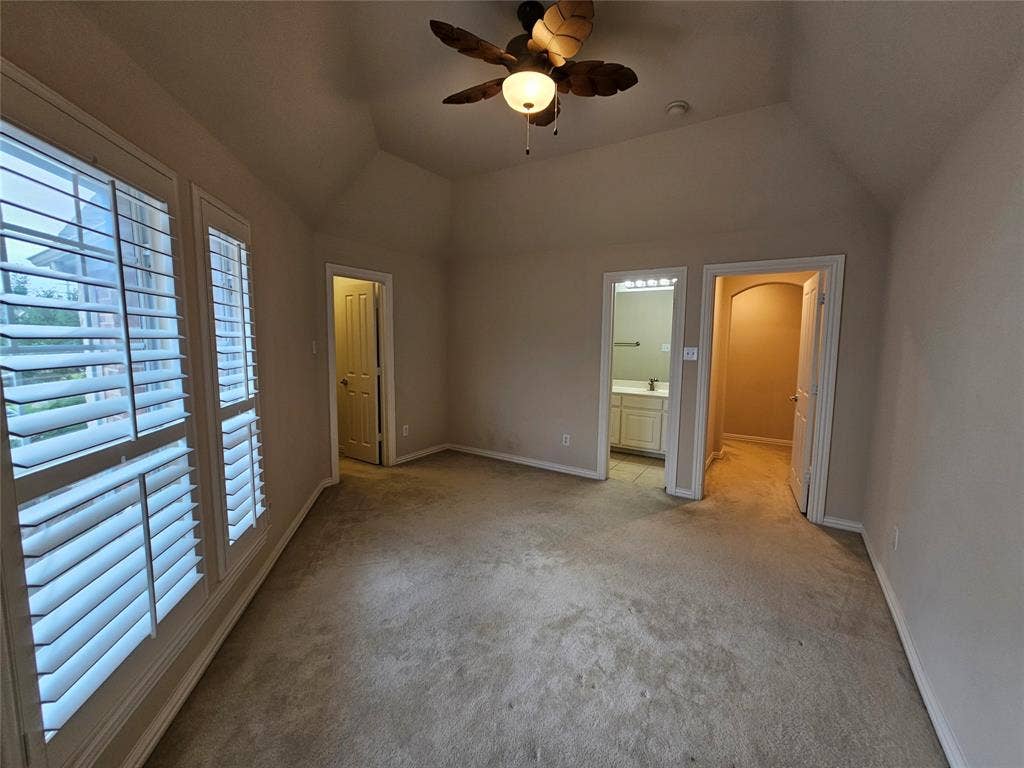 1009 Ricci Court, Irving, TX 75062 Vaulted ceiling with a ceiling fan, dual windows with plantation shutters, and light-toned carpeting