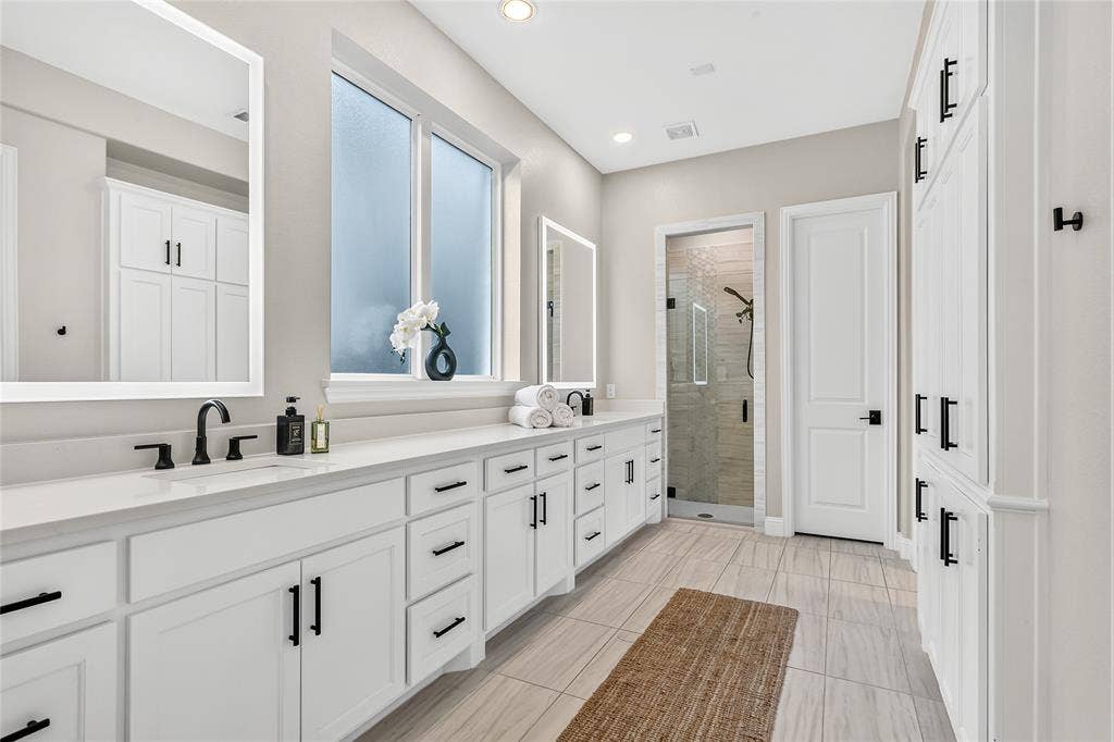 1581 Turnberry Drive, Prosper, TX 75078 Spa-like primary bath with backlit LED mirrors and a large window that fills the space with natural light.