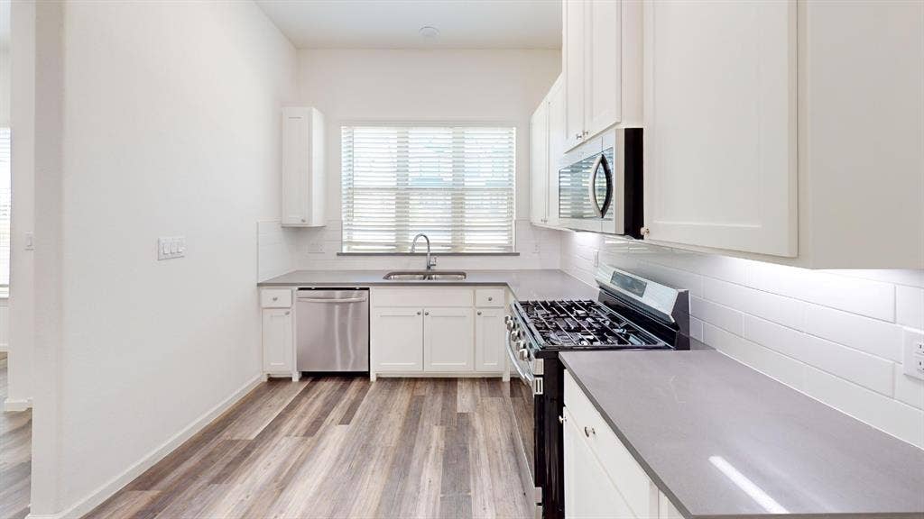366 Buck Ridge Drive, Frisco, TX 75068 Kitchen featuring wood-finish flooring, white cabinetry, sleek countertops, white subway tile backsplash, and stainless steel appliances