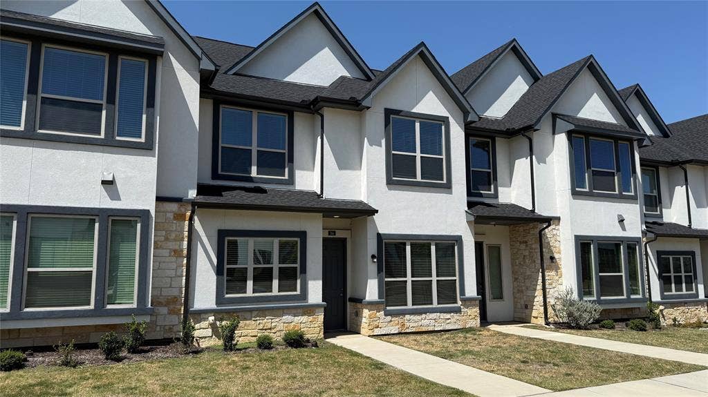 366 Buck Ridge Drive, Frisco, TX 75068 Contemporary townhome featuring a stucco and stone facade, dark framed windows, and a dark shingle roof