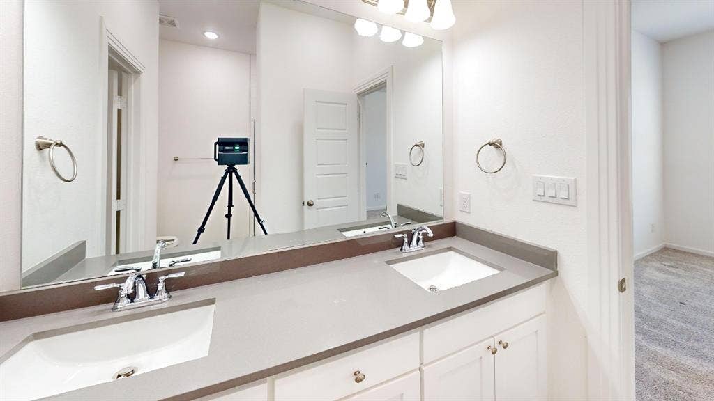 366 Buck Ridge Drive, Frisco, TX 75068 Dual undermount sinks with chrome fixtures, light gray countertop, white cabinetry with silver hardware, and wall-mounted vanity lighting
