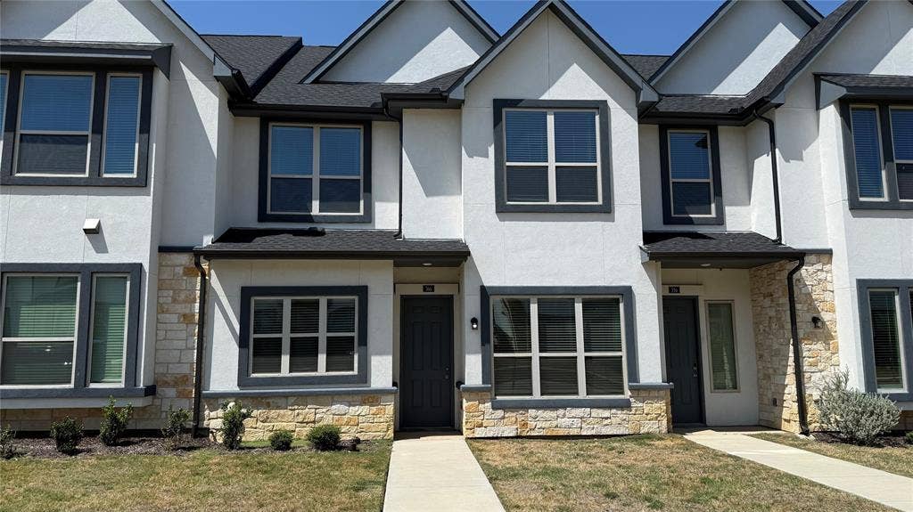 366 Buck Ridge Drive, Frisco, TX 75068 Modern townhouse exterior with white stucco siding, dark trim windows, and a prominent dark roof