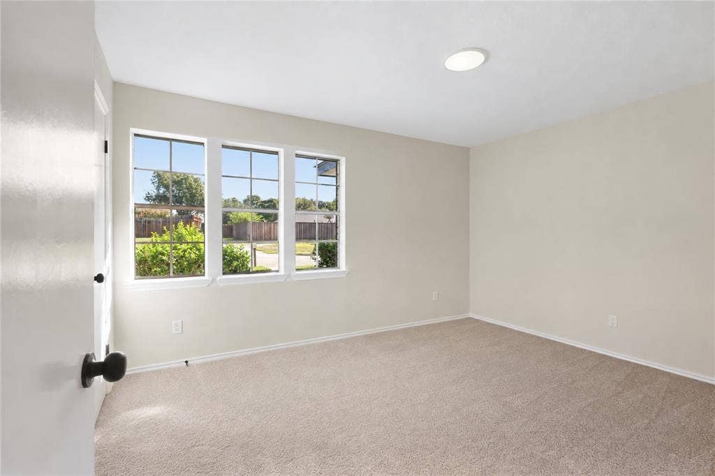 Neutral wall finishes, recessed ceiling lighting, light-toned carpet flooring, and a three-pane window with grid inserts