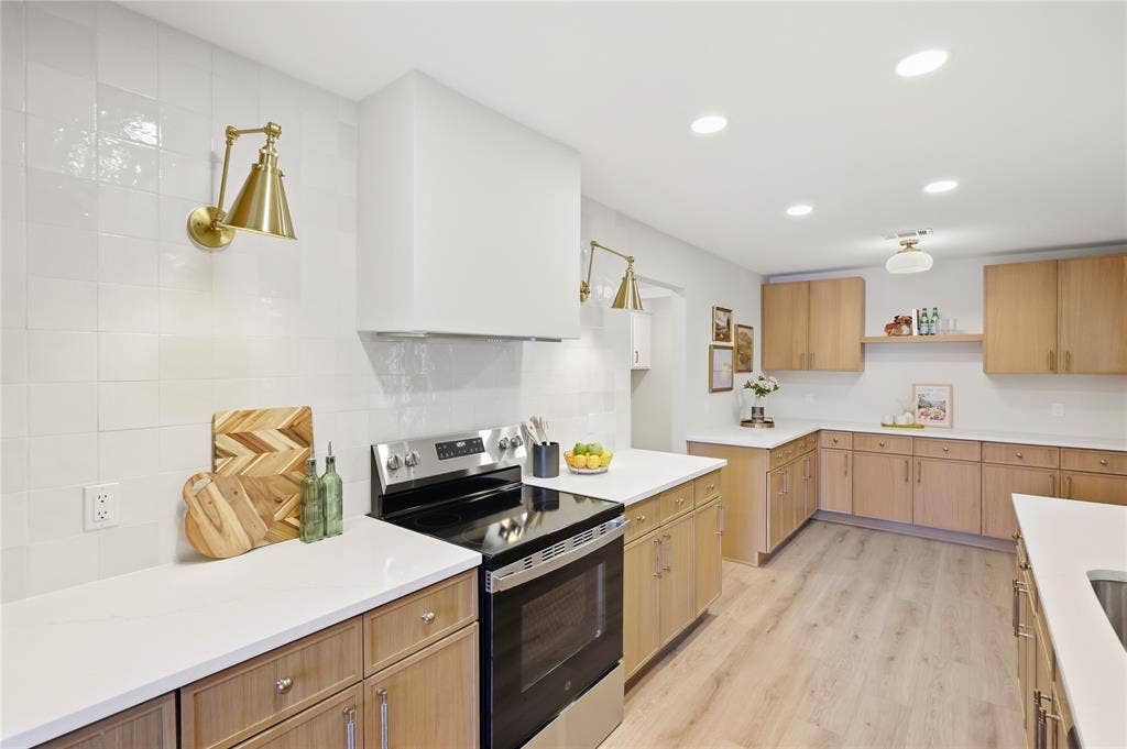Contemporary kitchen featuring a stainless steel range, white countertops, wood-finish cabinetry, and recessed lighting