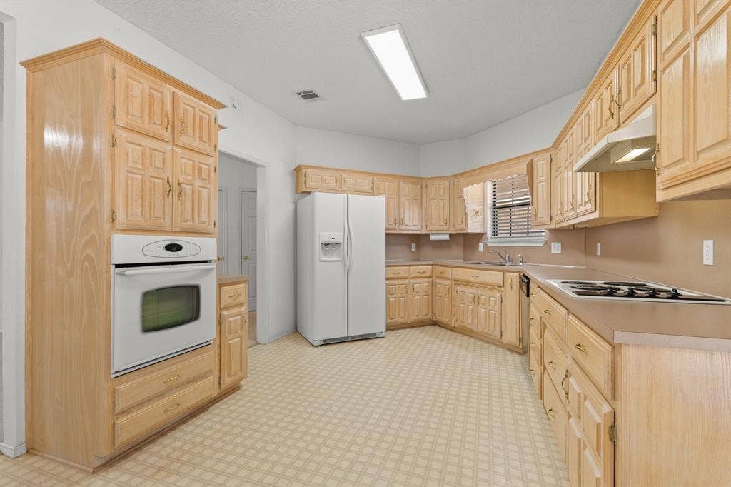 Kitchen featuring extensive light wood cabinetry, integrated oven, and a built-in cooktop