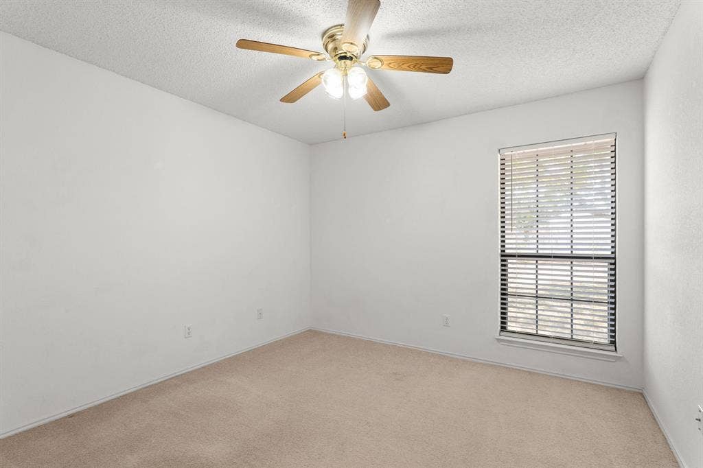 Recessed window with blinds, overhead ceiling fan with light fixture, and neutral carpeting